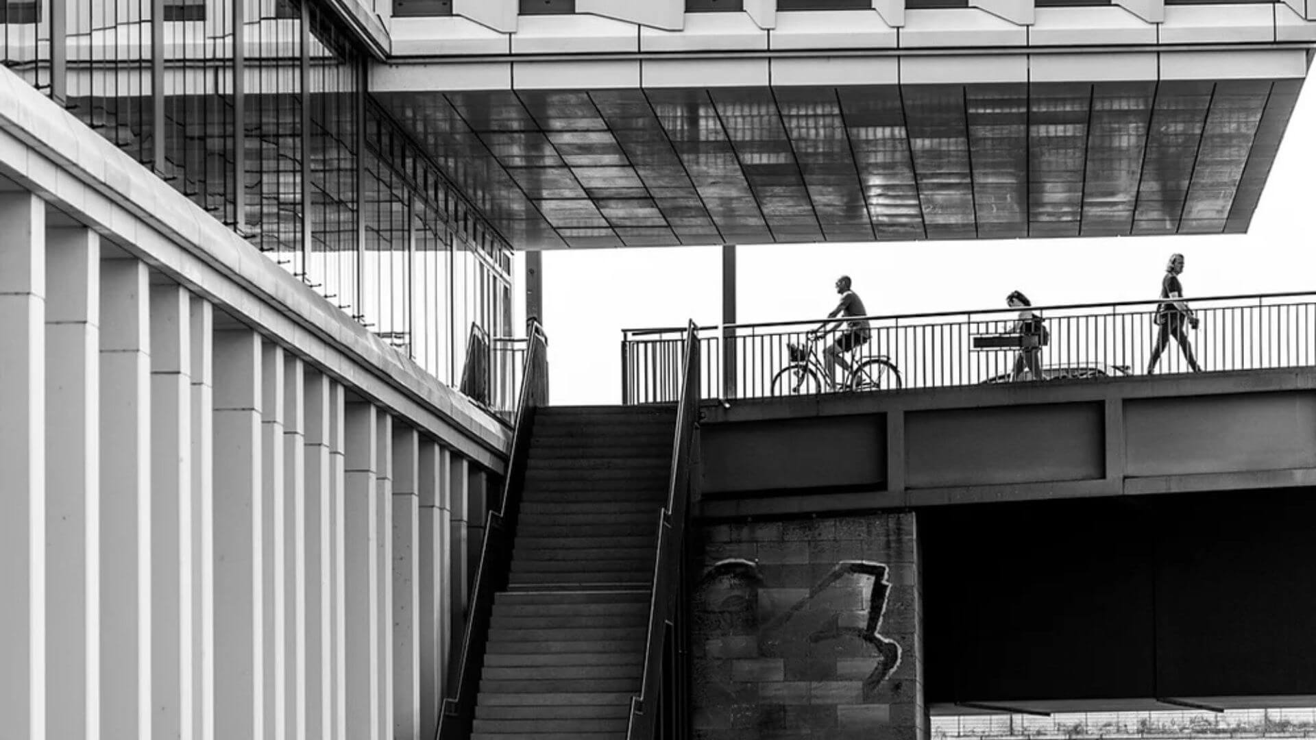 A group of people walking up and down the stairs beside a modern building.