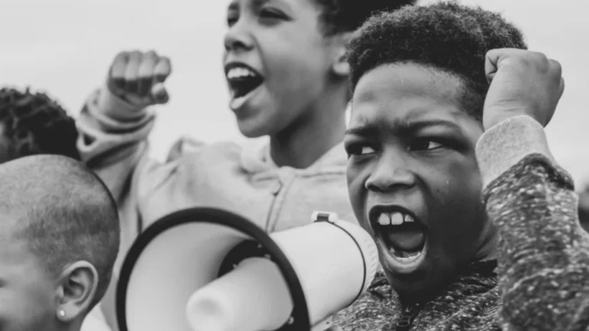 Black and white photo of children enthusiastically holding megaphones, expressing excitement and energy.