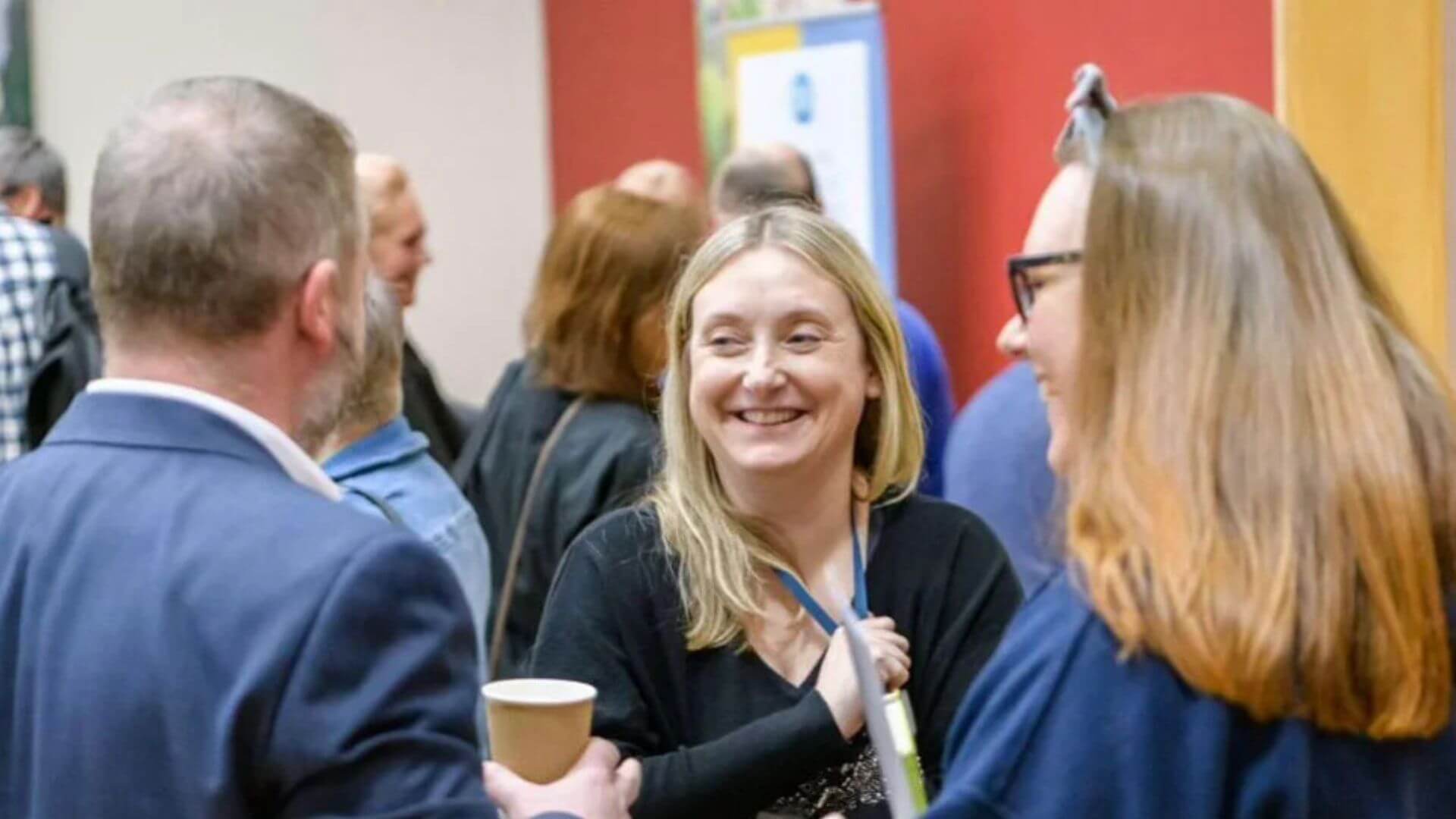 Attendees at an event, happily conversing and sharing smiles in a vibrant social setting.